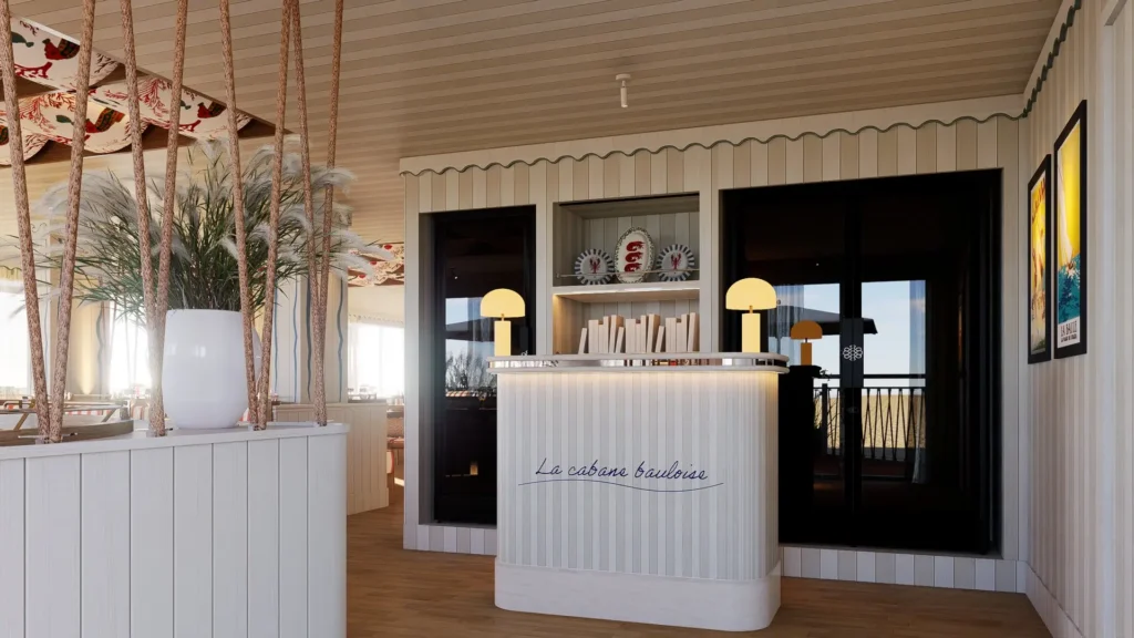 Réception du restaurant La Cabane Bauloise avec desk blanc arrondi portant le logo, plantes et vue sur la mer