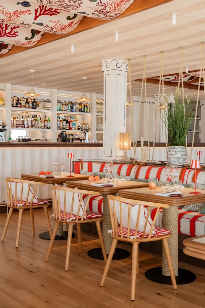 Bar bien achalandé, banquettes rayées, tables en bois à cordage et décor marin dans la salle du restaurant