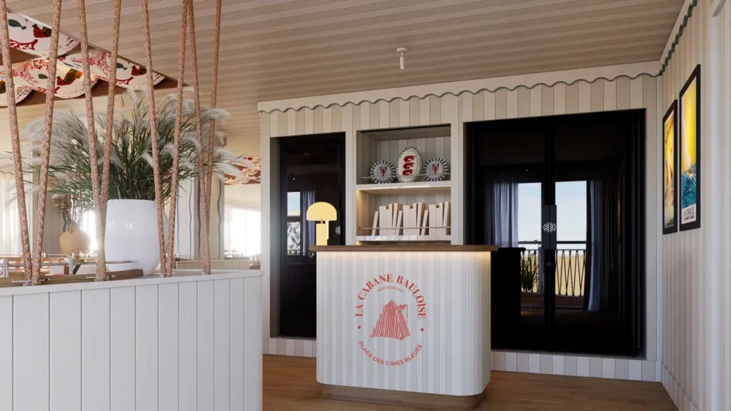 Hall d'entrée de La Cabane Bauloise avec desk blanc portant le logo rouge, étagères et portes vitrées donnant sur la mer
