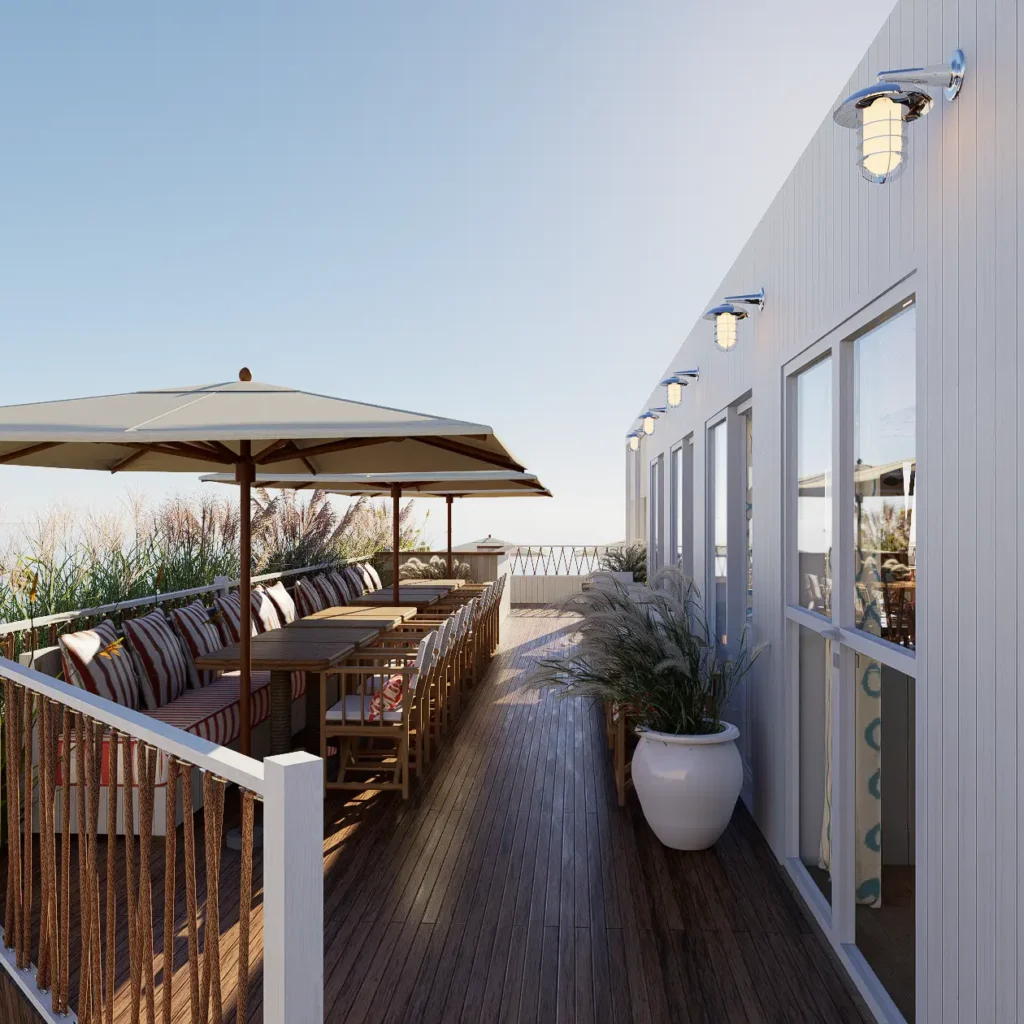 Terrasse extérieure en bois avec transats, parasols et vue dégagée sur la mer depuis le restaurant La Cabane Bauloise