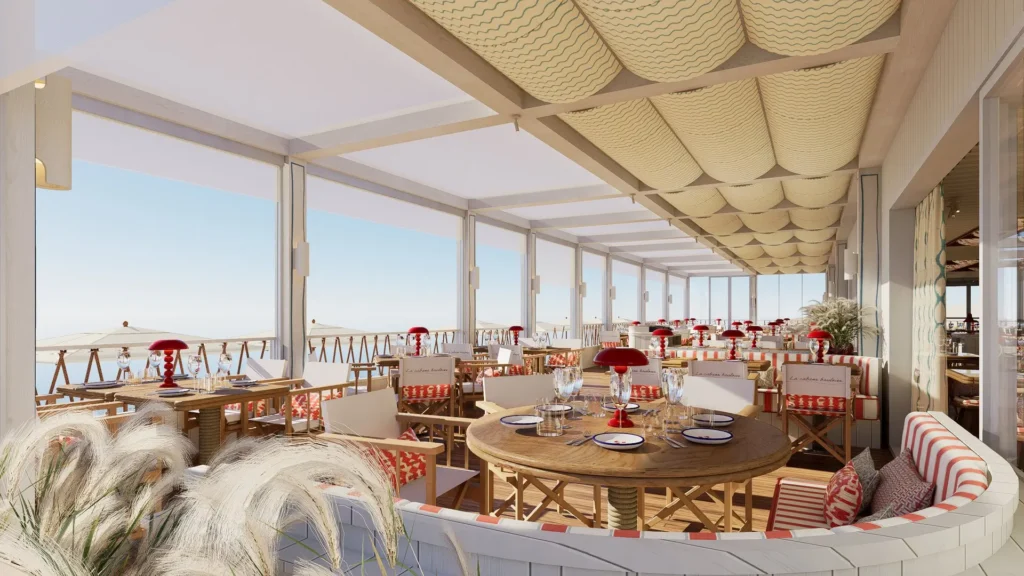 Grande terrasse vitrée du restaurant La Cabane Bauloise avec tables rondes dressées et vue panoramique sur la mer